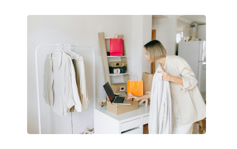 Woman managing an online store from home, packaging clothing orders and handling customer engagement for her business.